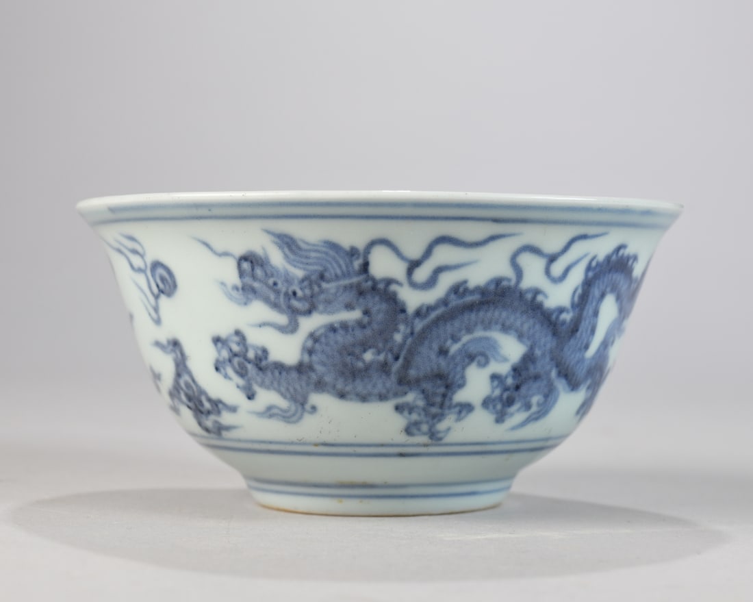 Chinese Blue and White Porcelain Bowl: Shallow, flared form with short foot, decorated with opposing dragons chasing flaming pearls amid clouds, the interior with a medallion dragon and a geometric diaper border at the rim; unmarked; likel