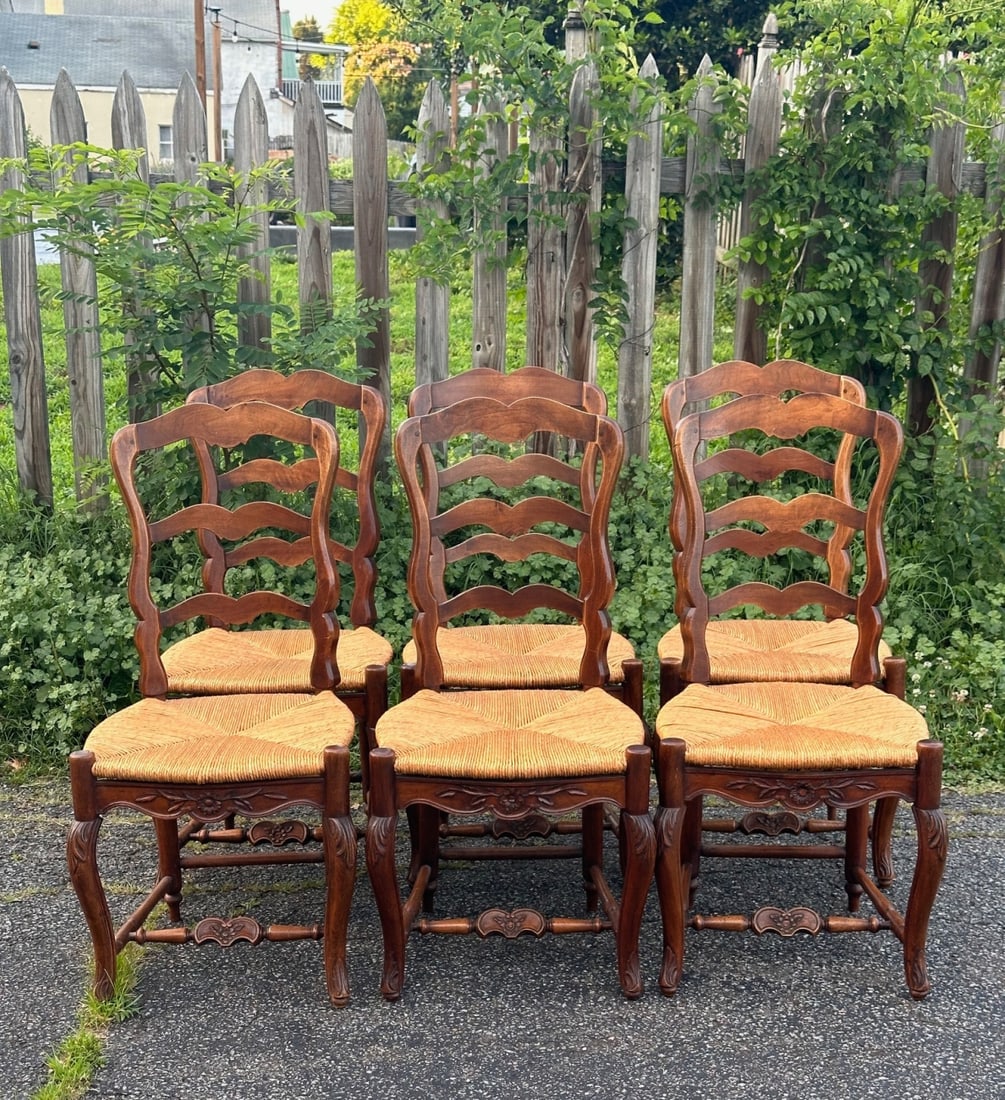 Set of Six French Provincial Style Dining Chairs: 20th century, each with shaped ladder backs, rush seats, floral and foliate seat rails, molded front posts transitioning to cabriole front legs with carved leaf ornament, shaped front stretchers