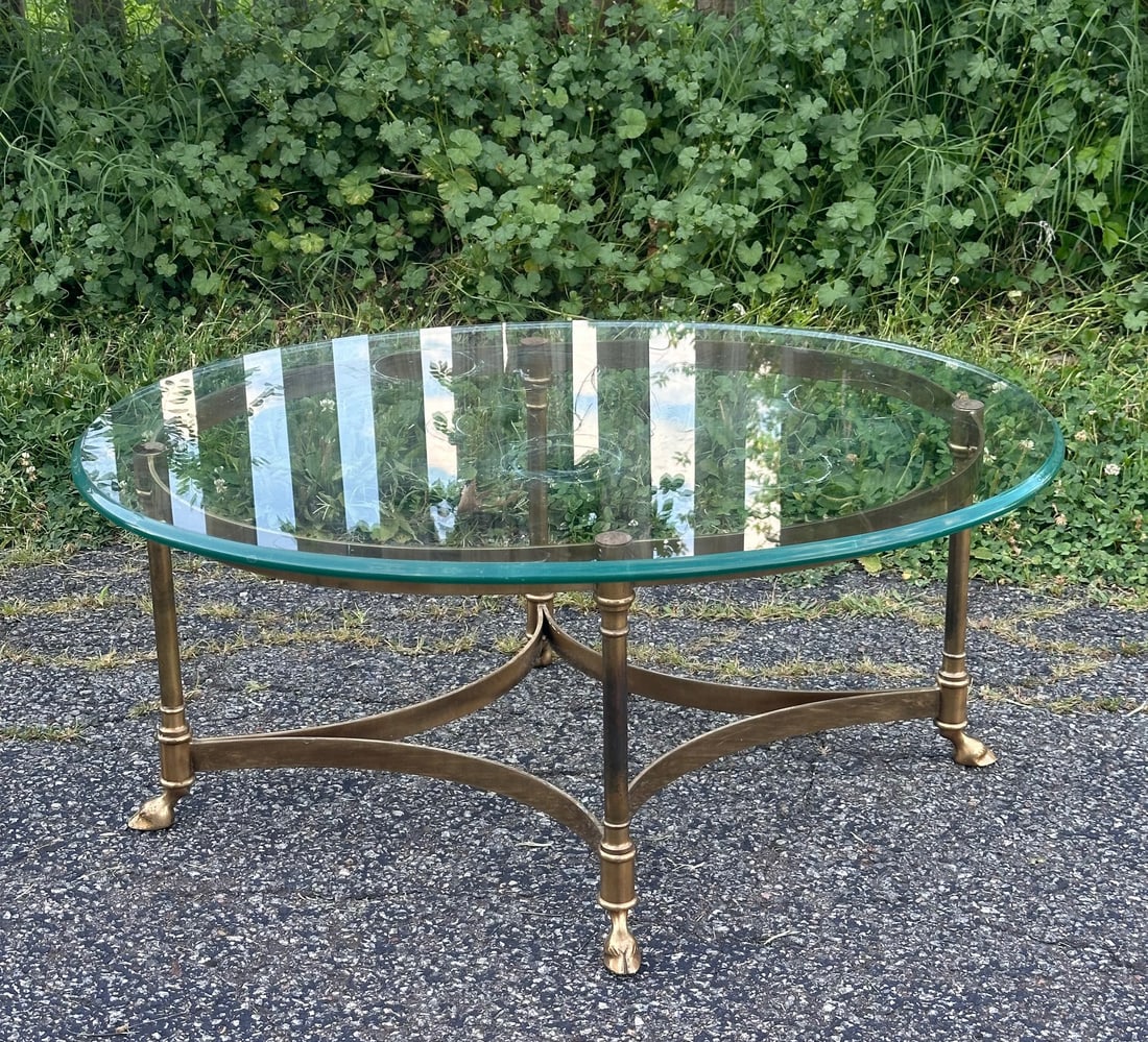 20th C. Oval Brass & Glass Coffee Table: Four leg brass frame with stylized paw feet supporting an oval beveled glass top. H: approx. 15", top approx. 34 1/2" x 26". Our primary recommendation is to arrange shipping yourself using Blue Ridge
