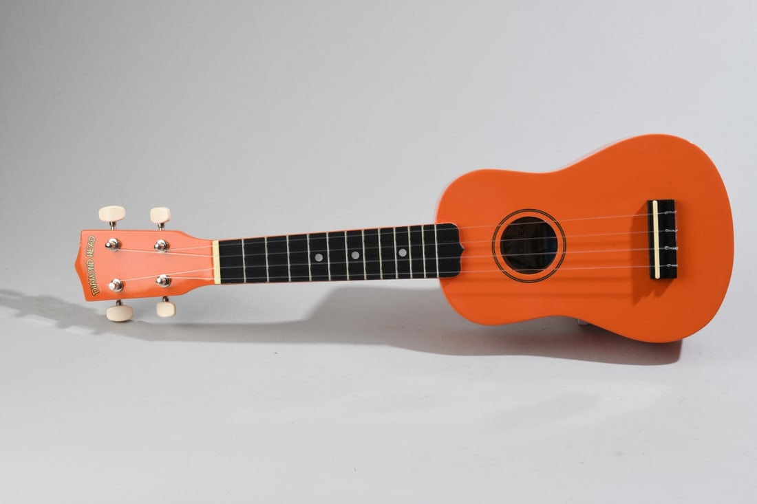 Diamond Head Orange Ukulele: In bright orange finish, labeled "Diamond Head" at headstock and interior label, fitted with four strings and open gear tuning machines. Includes matching orange zippered carry bag (some damage and