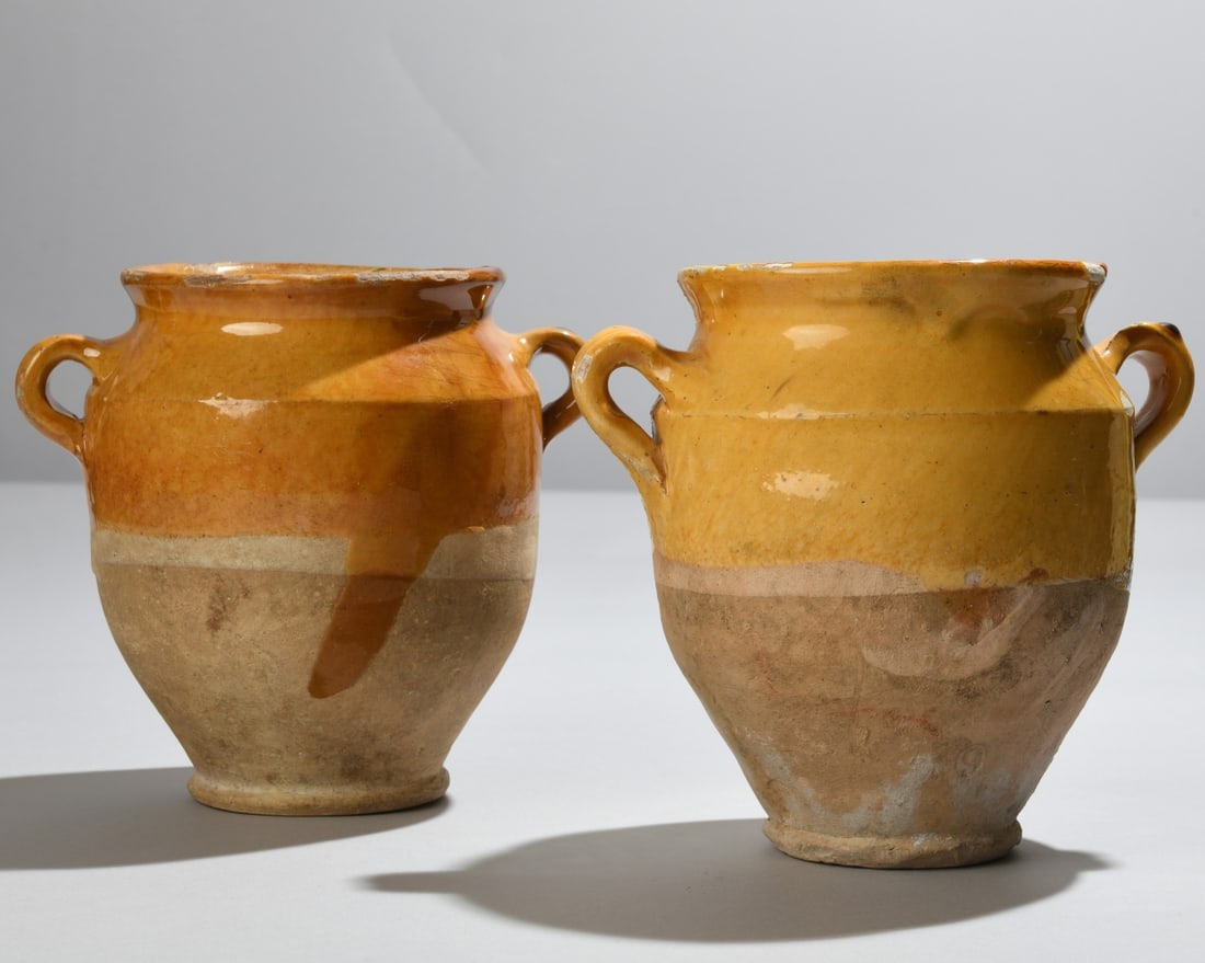Two Antique French Ochre-Glazed Confit Pots: Two antique French ochre-glazed earthenware confit pots with loop handles and tapered bodies. Likely late 19th to early 20th century. Exhibiting wear, glaze losses, and rim chips consistent with age