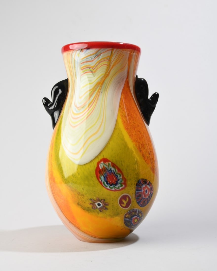 Murano Style Millefiori Glass Vase: A Murano style art glass vase with a flared rim, cased with a translucent red lip ring, body with swirling orange, white, and yellow ribbons interspersed with embedded multi-colored millefiori
