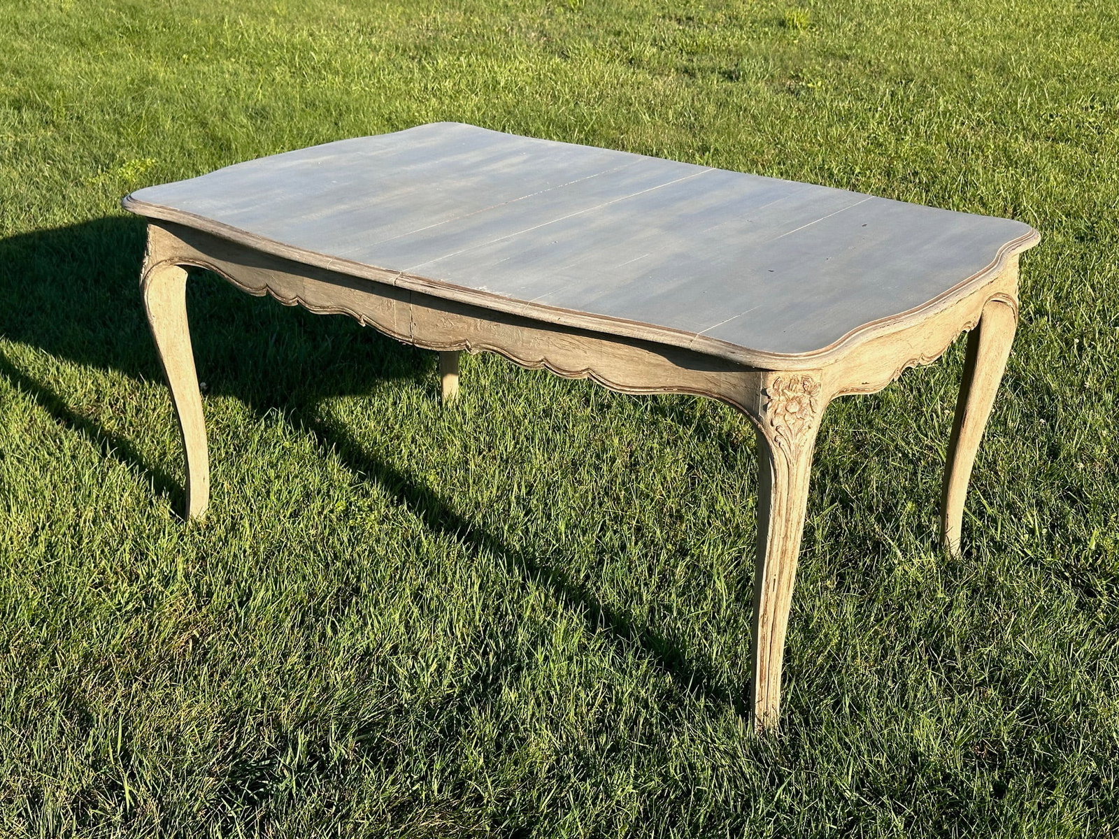 L 19th / E 20th C. Continental Rococo-Style Table: Carved wood with shaped serpentine top and scrolling cabriole supports with floral carving, finished in distressed cream and gray paint decoration, with two leaves, some minor wear, surface distress, 