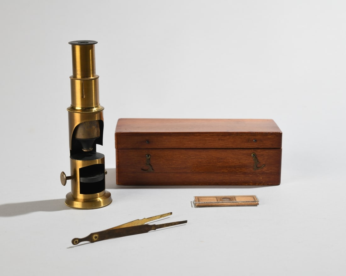 Antique Brass Drum Microscope: Small brass drum microscope, likely early 20th century, housed in a wooden case. Monocular brass body with focusing knob and lower mirror, accessories including tweezers and glass slides, similar in