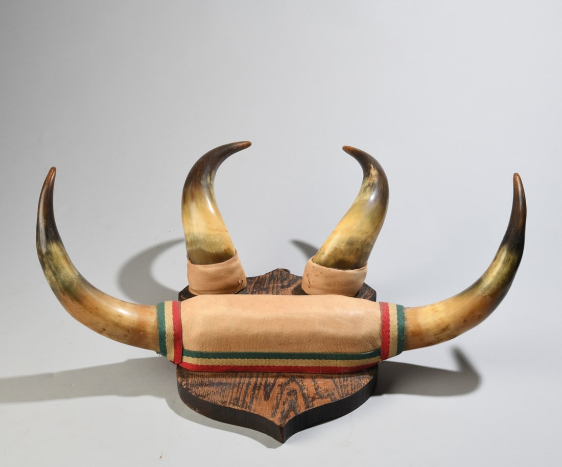 Horn Wall Mounted Hat Rack: Horns mounted to a shaped wood backboard with dark finish, some minor wear, scrapes to leather padding. Approx. 20" x 15" x 8 1/2". Provenance: the estate of John Long, highly regarded Virginia