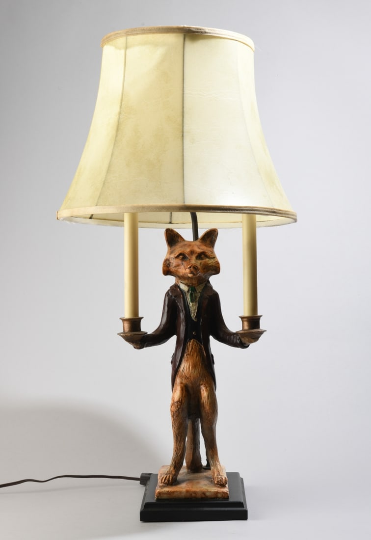 Contemporary Fox Form Table Lamp: Modeled as a fox standing upright and dressed in a red coat and scarf, supporting two faux candle forms, mounted to a rectangular base. Lamp powered on when tested. Scattered minor wear. Dimensions