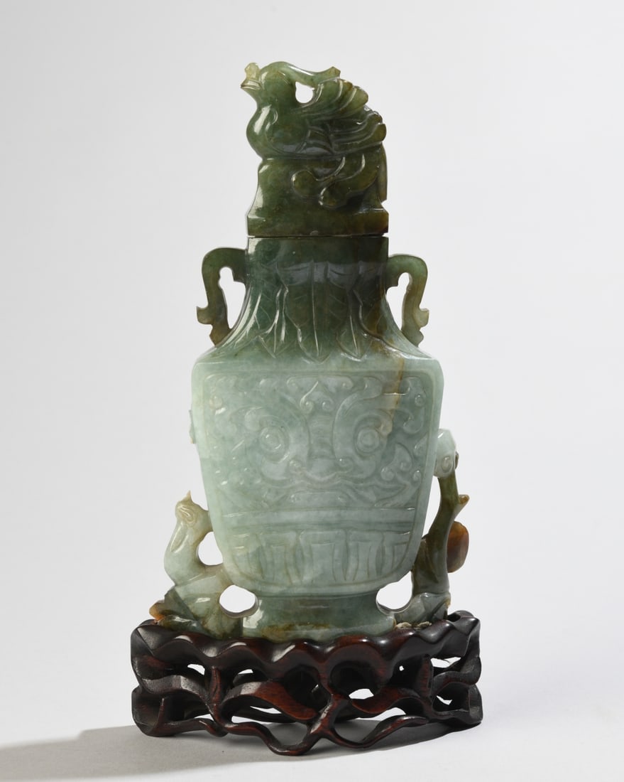 Chinese Carved Hardstone Lidded Vase: Damage including chips and losses to both handles, on wooden stand. Vase with lid: approx.6 3/4" x 3 1/2" x 1". Our primary recommendation is to arrange shipping yourself using Blue Ridge Pack &