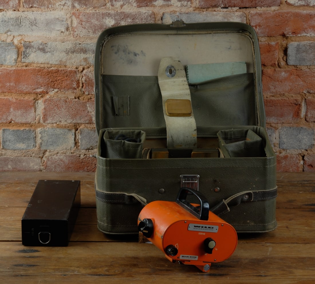 Wild Heerbrugg Optical Surveying Instrument: Swiss-made orange binocular-form instrument by Wild Heerbrugg, bears the Wild Heerbrugg nameplate and serial number 53546, accompanied by a separate black control or power unit, in fitted case with ac