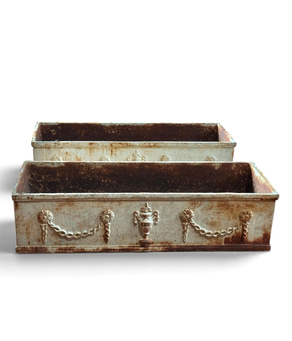 Pair Cast Iron French Neoclassical Style Planters: A matching pair of vintage French Neoclassical style cast iron planters. Each features cast relief decoration of a central urn flanked by draped floral swags and rosettes, with bottom drainage holes.