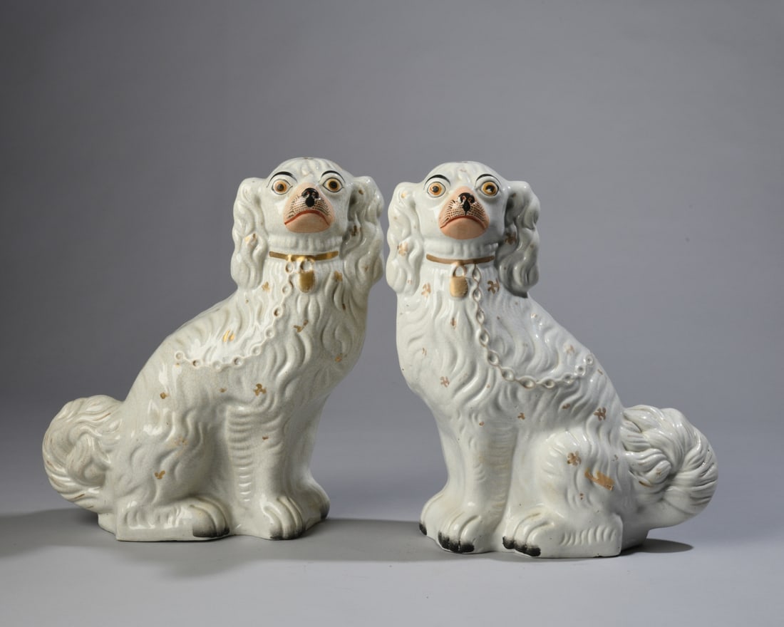 Pair of Victorian Staffordshire Pottery Spaniels: White glaze, painted facial details, gilt collars, each with "1" to underside and drilled backsides, all-over crazing and minor glaze flakes near toes. Each approx. 12 1/2" x 9" x 4". Our primary reco
