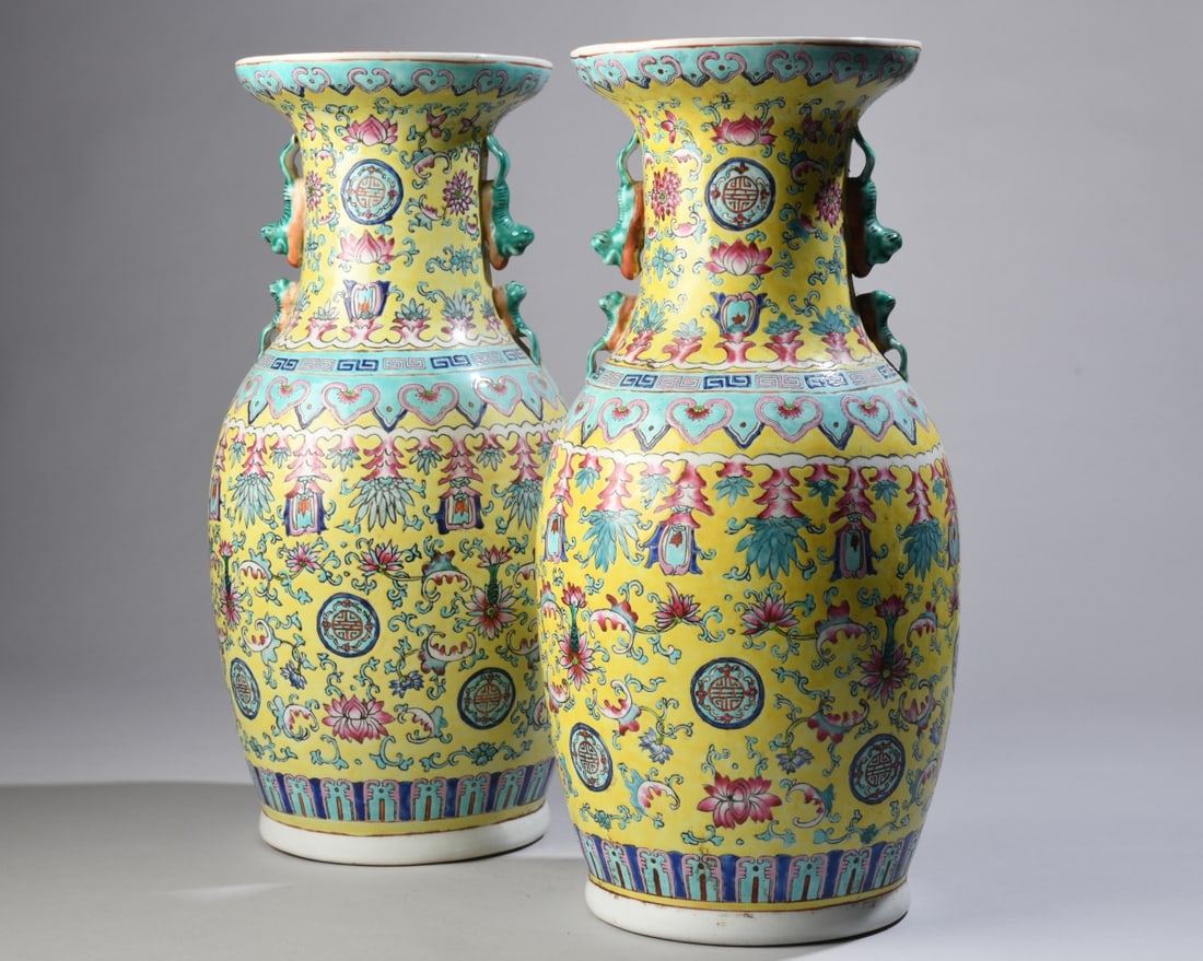 Pair of Yellow Ground Famille Rose Vases: A matching pair of baluster form vases featuring vibrant yellowground bodies, molded double chilong handles, and all over enamel decoration of stylized lotus scrolls, ruyi borders, and Shou