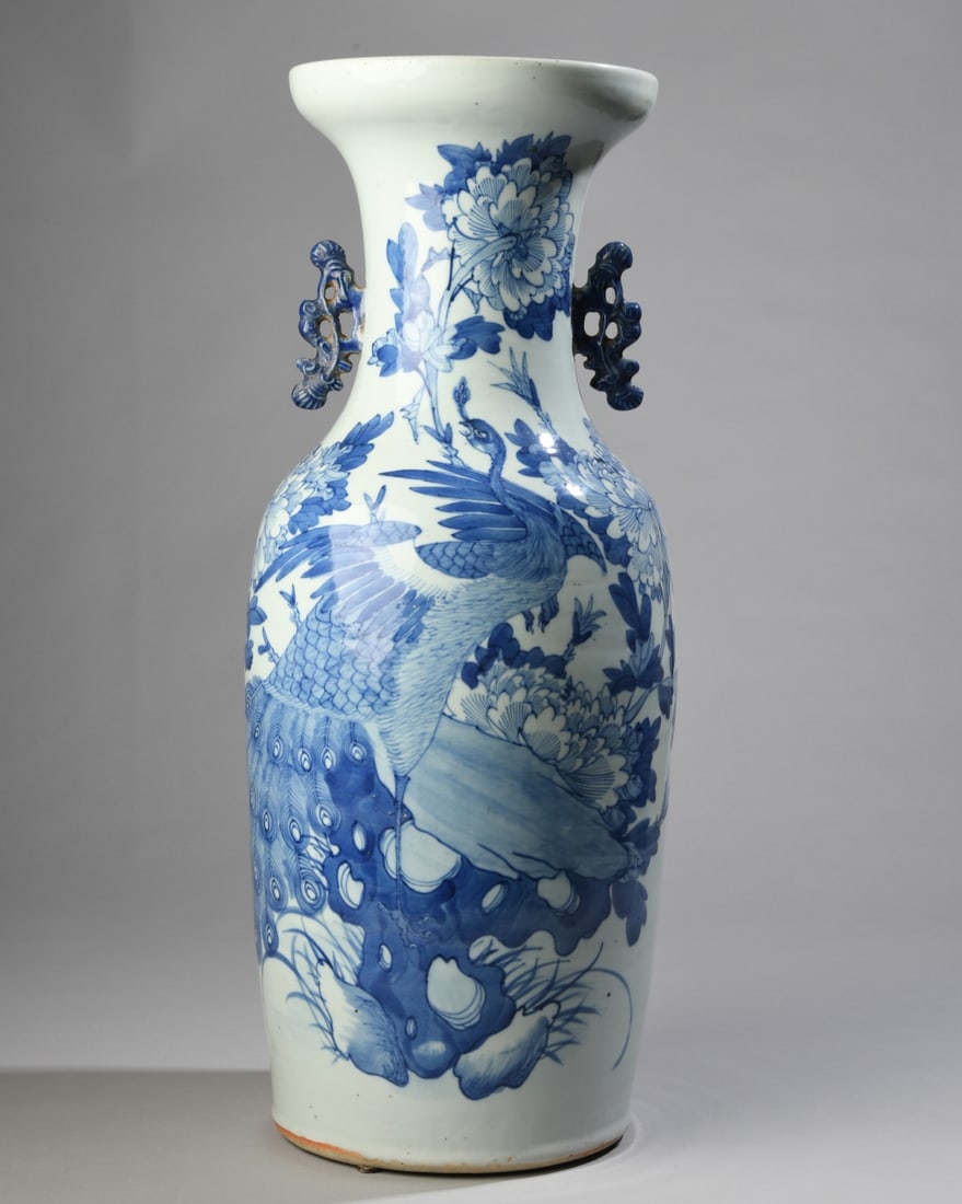 Chinese Blue and White Porcelain Vase: A large baluster form vase with stylized openwork handles at the neck, painted underglaze in dark cobalt blue tones over a grayish white ground. The primary scene depicts a peacock perched alongside l