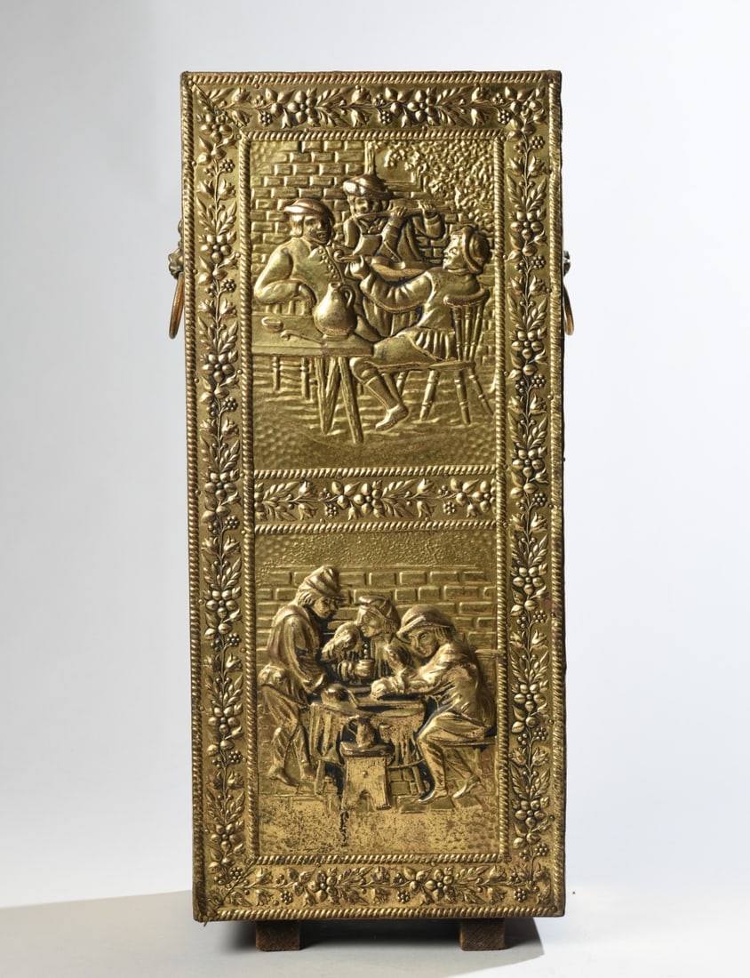 Continental Embossed Brass Clad Umbrella Stand: Early 20th century wooden umbrella or cane stand clad in brass, with removable metal drip tray, the front decorated with tavern scenes in the Dutch/Flemish style, and the sides with lion mask ring