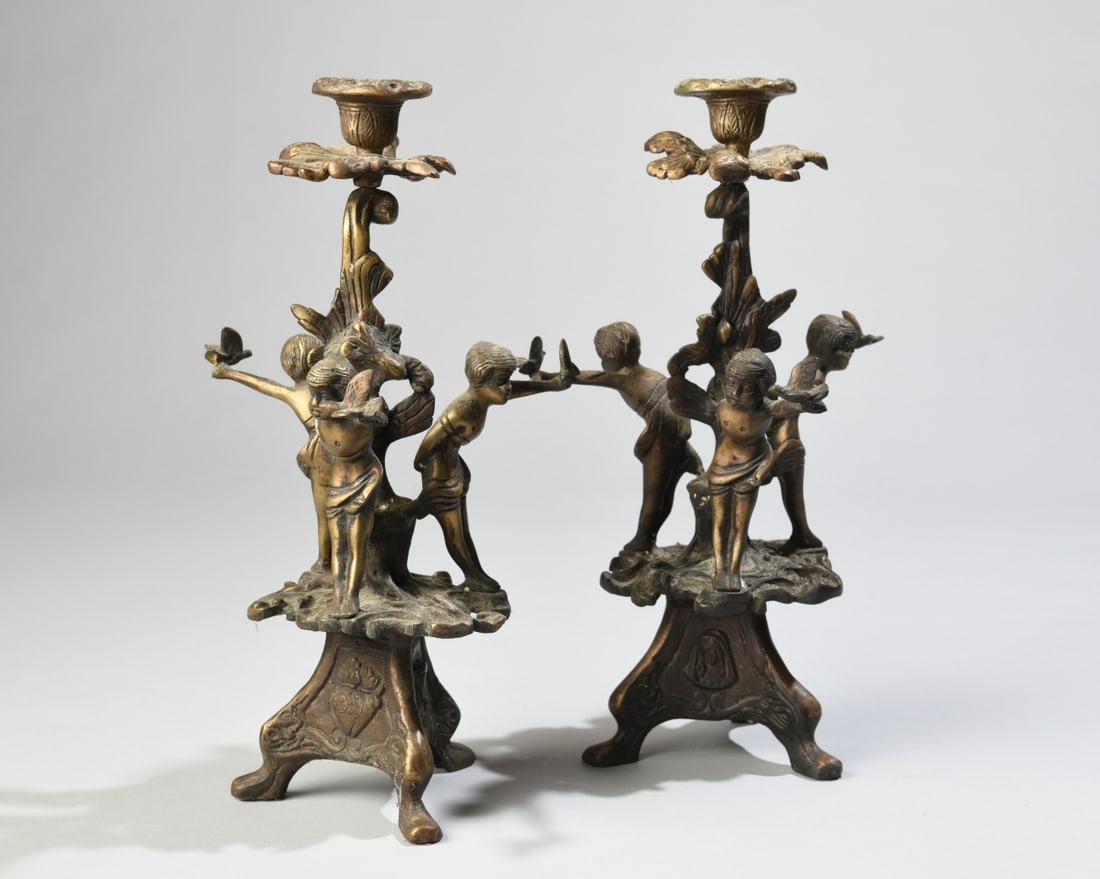 Pair of Continental Rococo Revival Figural Candles: Late 19th / early 20th century, bronze or brass patinated candlesticks with figures holding birds beside a flowering standard, some surface wear, oxidation, dust and minor bends / losses consistent