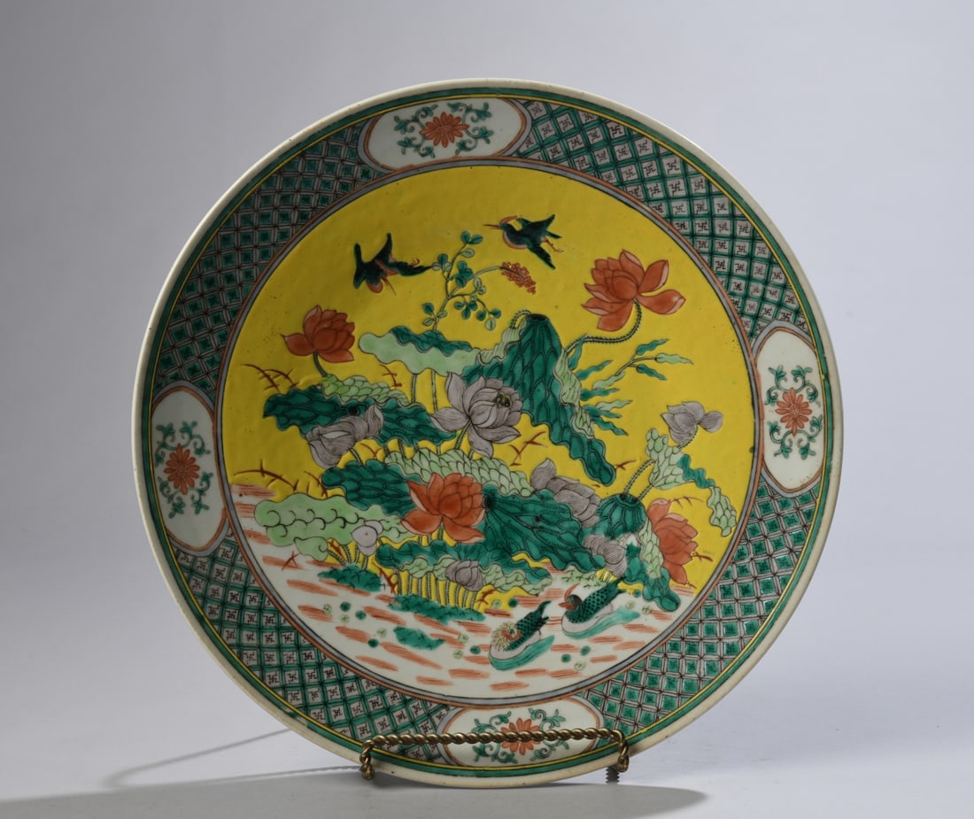 Chinese Famille Verte Charger: Qing dynasty, likely 19th century. Decorated with a yellow ground lotus pond scene with ducks and other birds among flowers, surrounded by a green and black swastika pattern border with floral