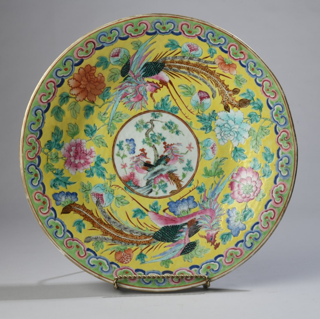 Chinese Famille Rose Phoenix Charger: Qing dynasty, likely 19th century, with yellow ground decoration of phoenixes among flowering peonies and foliage, centered by a circular reserve, border with stylized motifs, underside with iron red