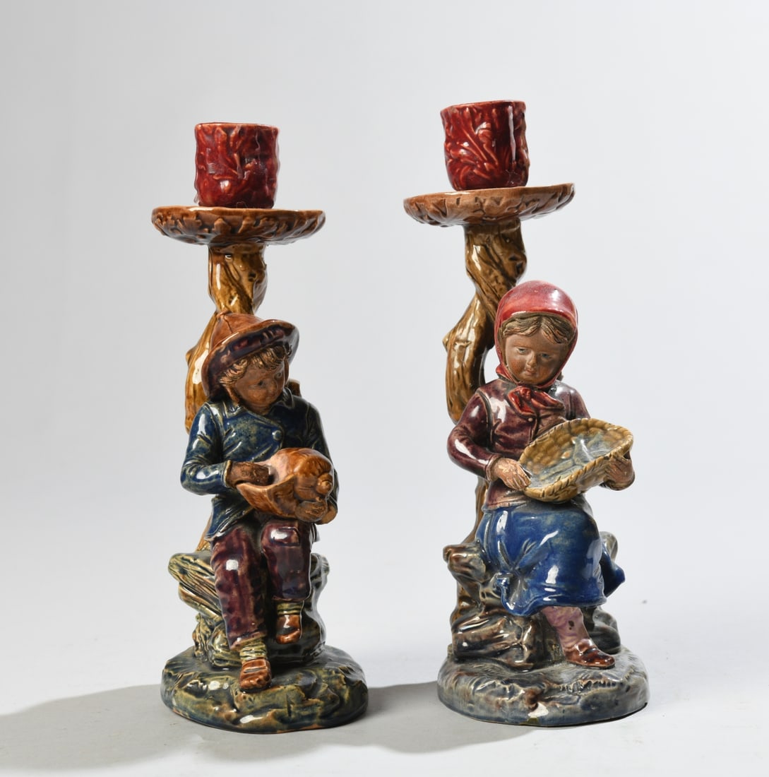 Pair of Figural Glazed Ceramic Candlesticks: Modeled as seated children beneath tree-form candle cups, decorated in polychrome glazes. Impressed BO 991 and BO 992 to undersides. 20th century. Minor surface wear and glaze irregularities. Our prim