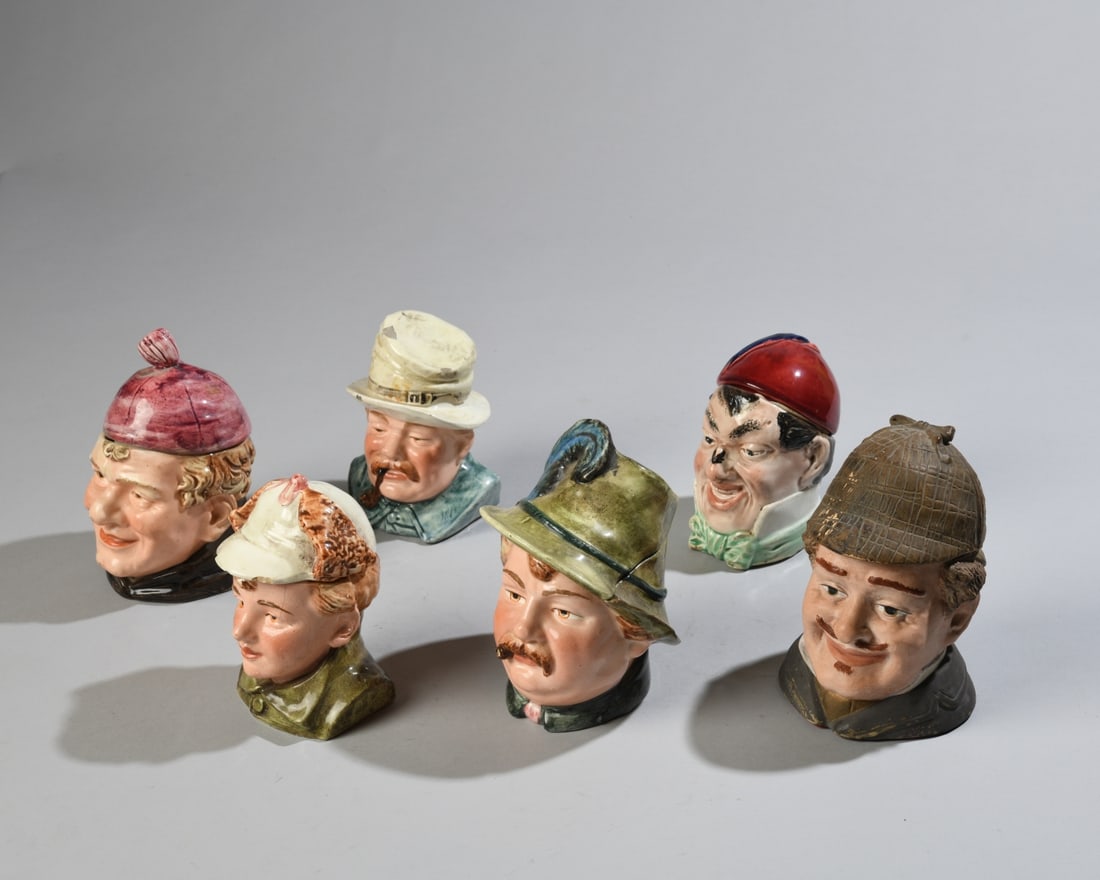 Six Figural Tobacco Jars: Late 19th / early 20th century figural ceramic tobacco jars, each modeled as a character head with removable lid, one marked BB / 355 / DEP for Bernard Bloch. Some chips and cracks / all in as-found