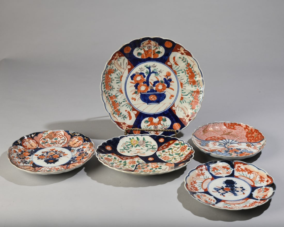 Five Japanese Imari Porcelain Plates: 19th Century and later, of varying sizes with scalloped rims and polychrome decoration in underglaze blue, iron red, green, and gilt. Undersides with underglaze blue decorative motifs. Some chips and