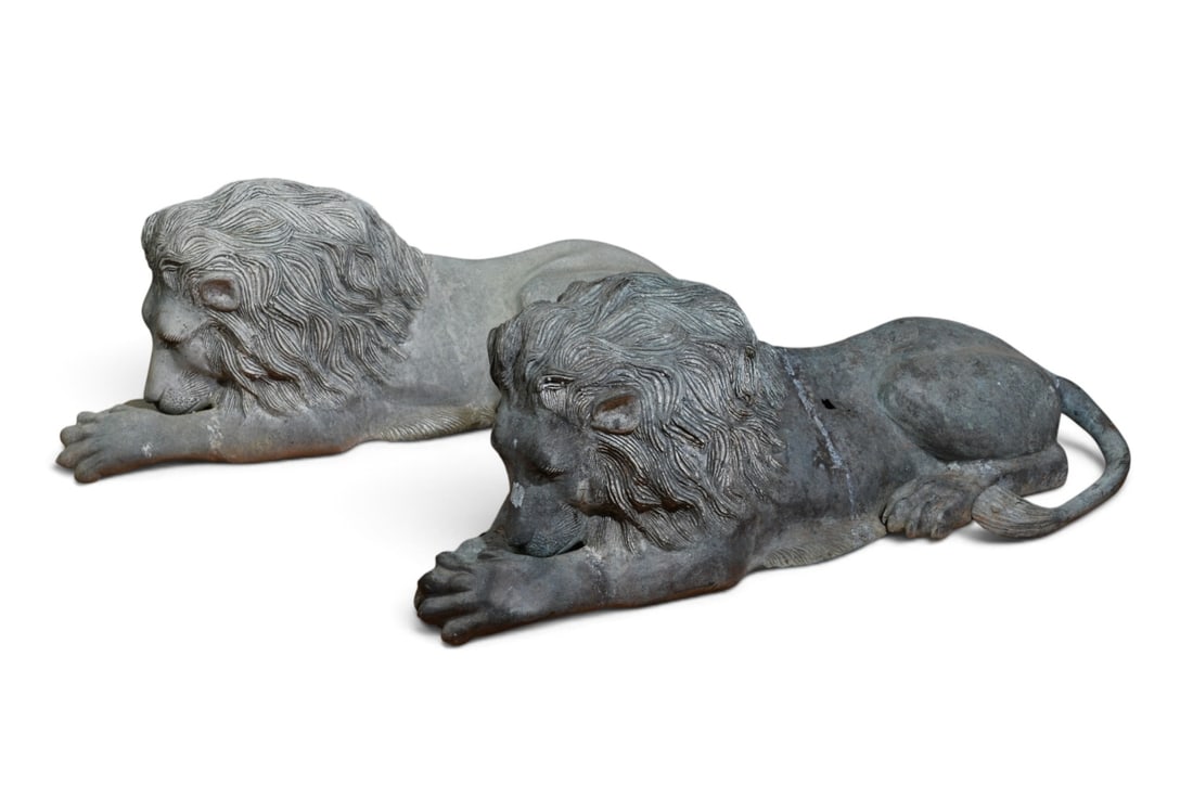 Pair of Vintage Cast Metal Garden Lions: Pair of hollow cast metal garden lions in a classic reclining pose, with a weathered grey finish, One surface hole to the back of one lion, and chipped tail to the other. Dimensions approx. 37" x 15"
