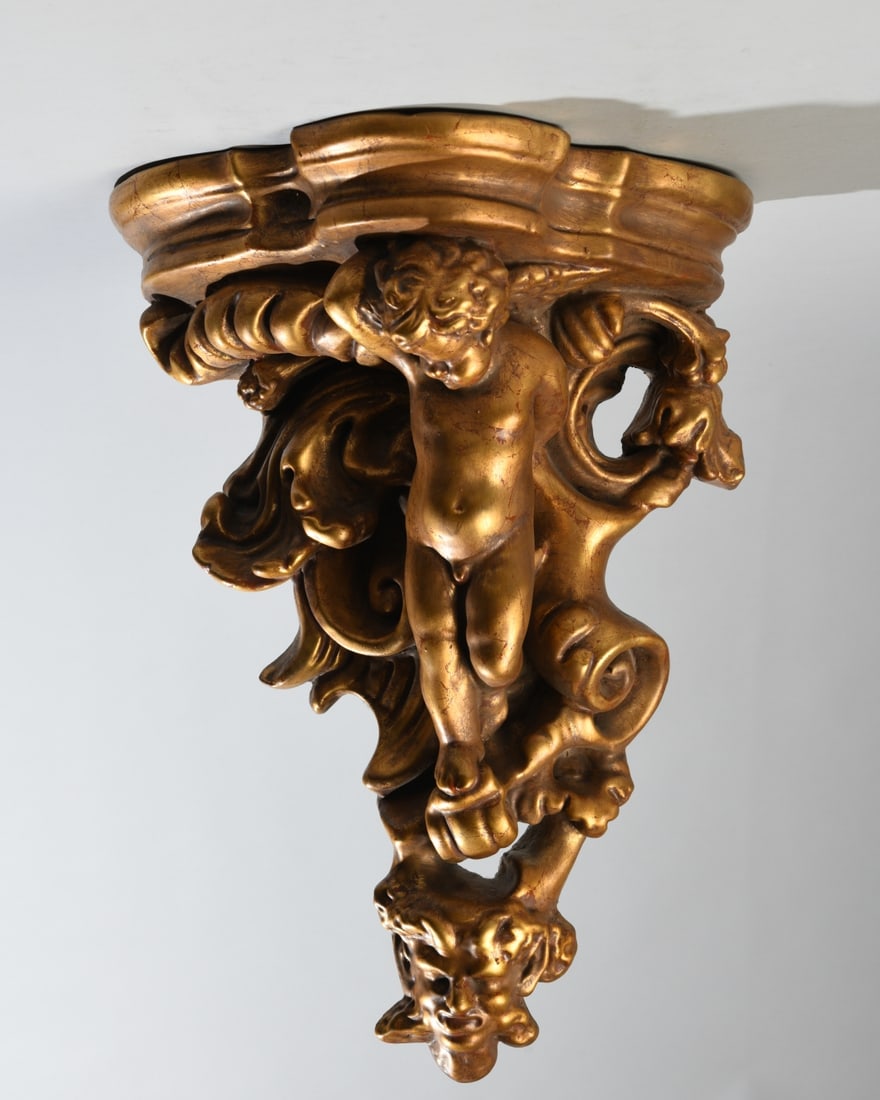 Vintage Rococo Revival Wall Bracket: Rococo Revival gilded wall bracket shelf featuring a sculptural cherub set among scrolling acanthus leaves and shellwork. Crafted from molded chalkware/clay composition, Dimensions approx. 17 1/2" x