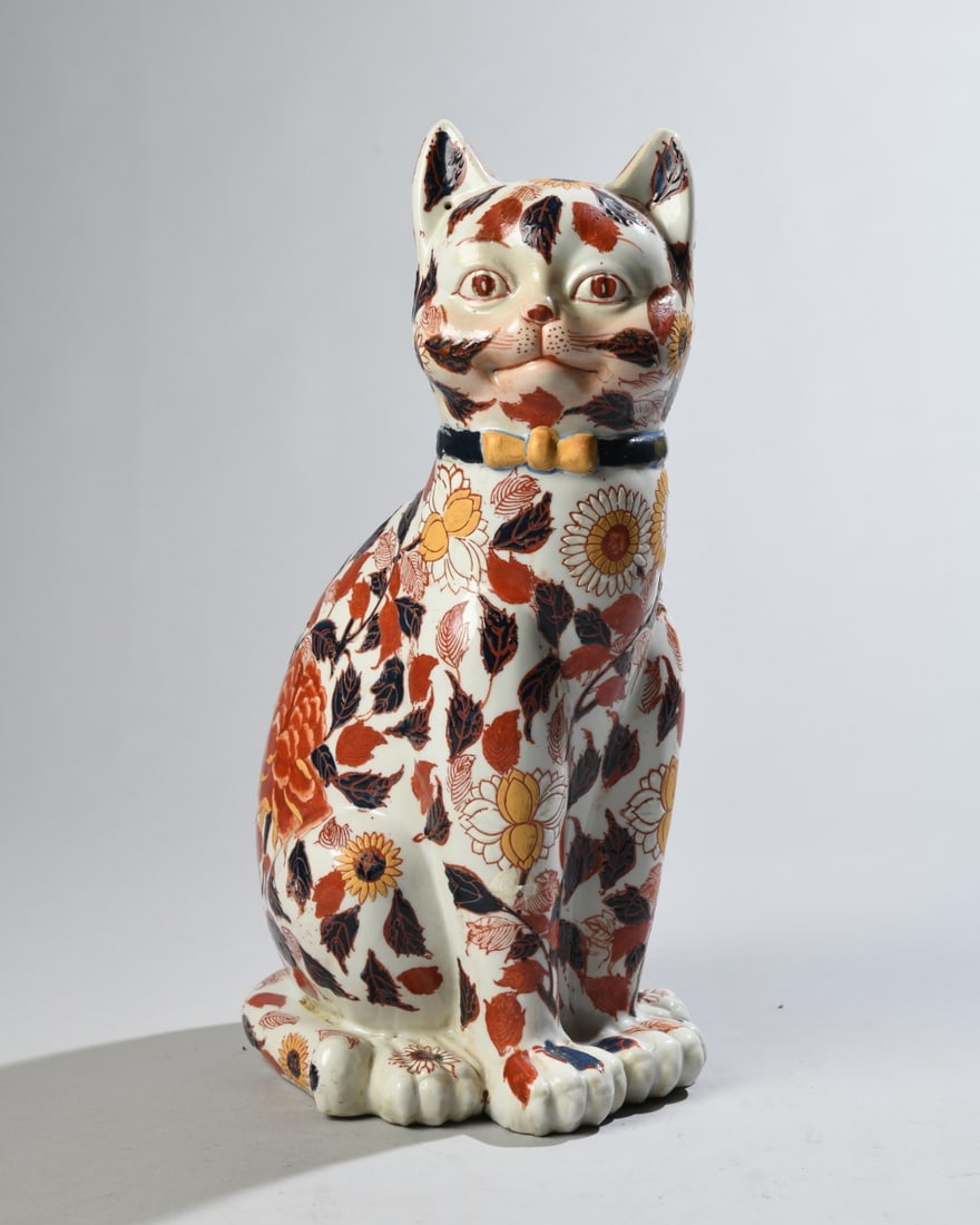 Chinese Imari Style Porcelain Cat: 20th century, Chinese porcelain cat in the Japanese Imari taste decorated throughout with floral and foliate motifs and wearing a painted collar with bow. Underside with red inscription. Minor
