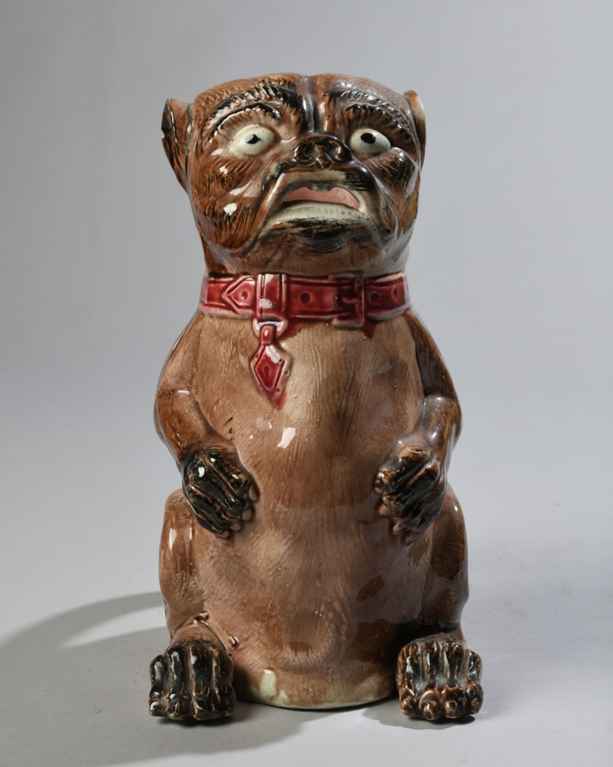 Majolica Pug Dog Figural Pitcher: Late 19th/early 20th century, unmarked. Damage to foot, chip to rim at ear, hairlines and crazing. Dimensions: approx. 10" x 8" x 5 1/4". Our primary recommendation is to arrange shipping yourself usi
