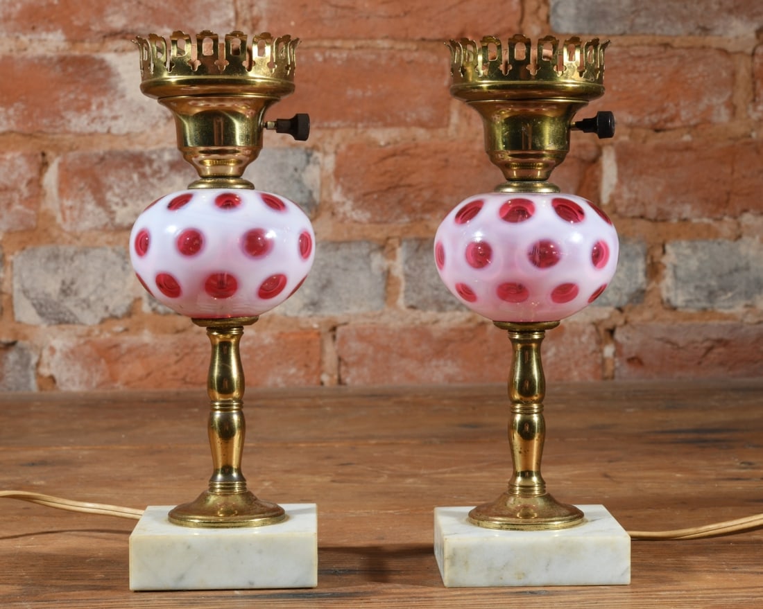 Pair of Cranberry Coin Dot Lamps: Pair of cranberry glass lamps on brass stems and square white marble bases with pierced brass shade rings. Dimensions approx. 9 1/2" x 3 1/8" x 3 1/8". Our primary recommendation is to arrange