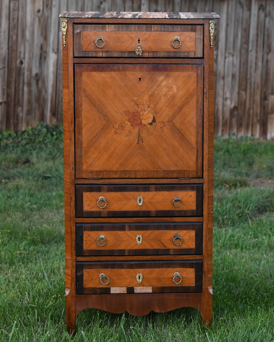 Louis XVI style Secretaire a Abattant: A French drop-front secretary desk with a contoured marble top over a single upper drawer, a fall-front desk panel, and three lower drawers. Features floral marquetry, parquetry paneling, and cast-bra