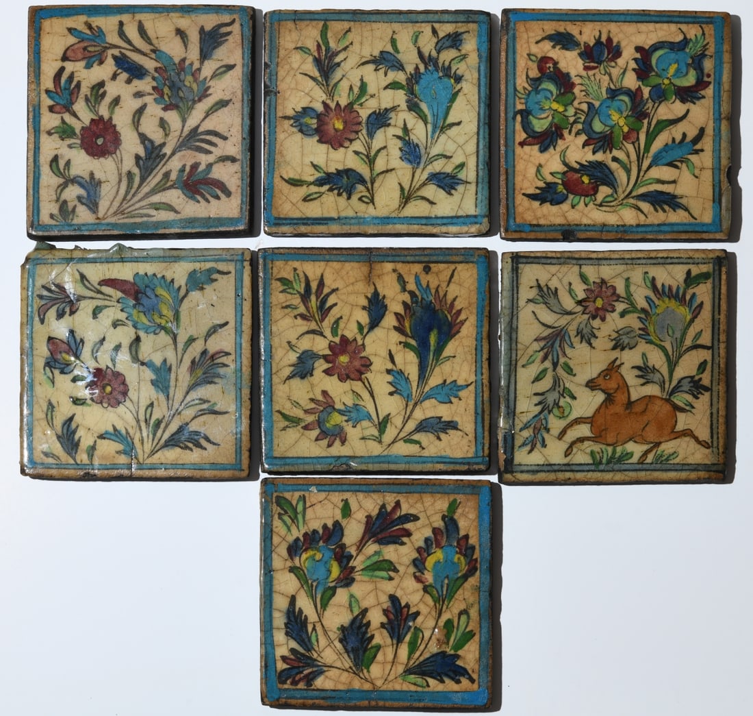 Seven Antique Qajar Persian Pottery Tiles: 19th century, each of square form and decorated in polychrome cuerda seca glazes with flowering sprays, one tile additionally decorated with an animal among foliage. Backs with dark coating and