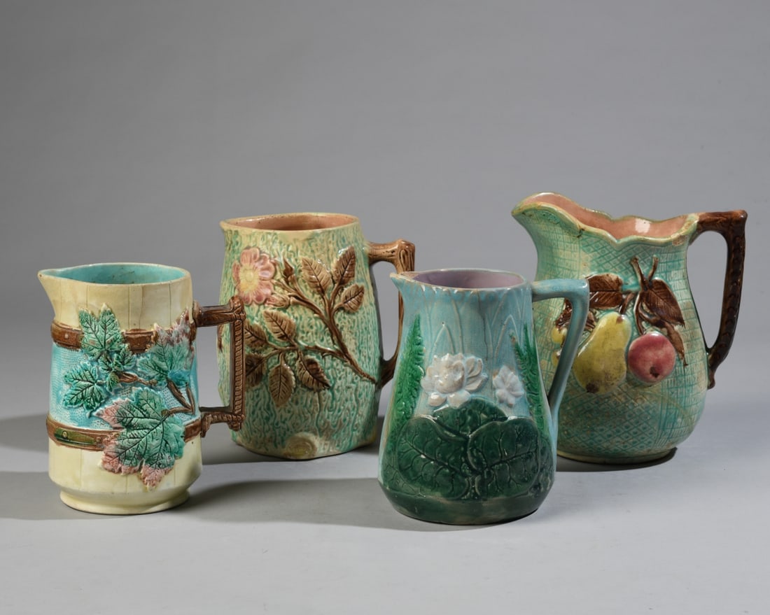 Four Majolica Pitchers: Late 19th/early 20th century, with floral, fruit and foliage decorations, unmarked. Crazing, staining, glaze losses, and rim chips. Largest dimensions: approx. 8" x 7 1/4" x 4 1/2". Our primary