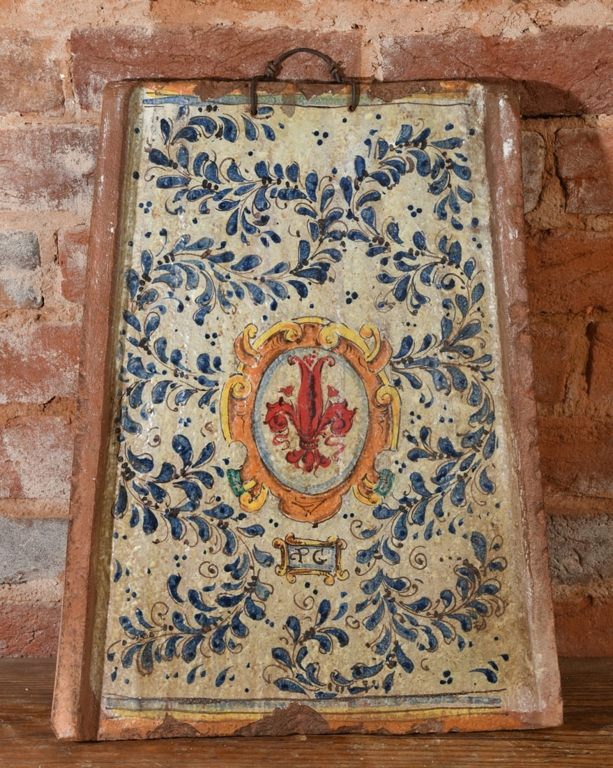 Italian Maiolica Armorial Wall Plaque: Rectangular tin-glazed earthenware plaque, the long sides turned up, painted in cobalt and manganese with a foliate wreath enclosing an ochre strapwork cartouche and the red Florentine lily.