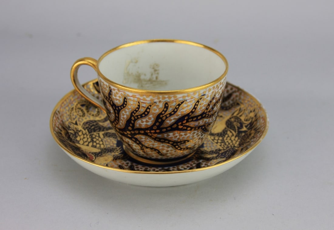 Antique English Porcelain Cup & Saucer: English gilded and enamel decorated porcelain cup and saucer, circa 1800, decorated within a Chinese manner with dragon or possibly a griffin. Unusual encre de chine decoration on the interior of the 