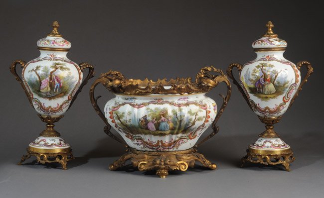 19th C. Porcelain and Ormolu Bowl and Urns: 19th C. Continental porcelain and ormolu centerpiece bowl and urns. Mark on centerpiece partially obscured by ormolu. Scenes of ladies in garden and courting couples. One lid cracked and repaired. Cen