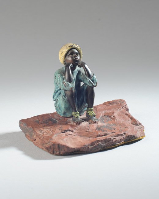 Franz Bergmann Austrian Bronze Boy: Cold painted bronze of North African boy sitting on a rock formation, with Bergmann's characteristic mark of "B" in an urn, circa 1915. H: approx. 3 1/2". W: approx. 4 3/4". D: approx. 3 1/4".