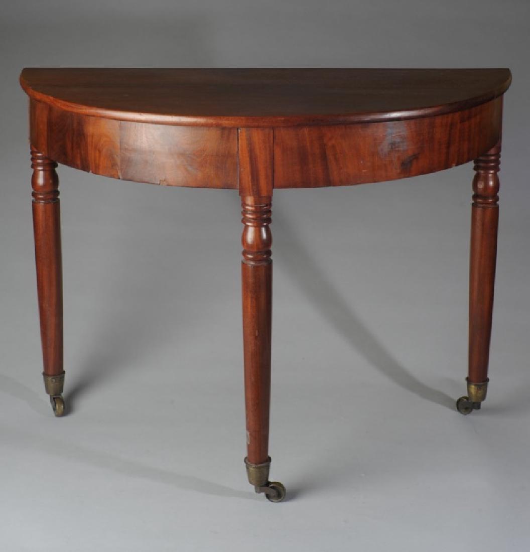 Sheraton Style Demilune Table: Walnut, three turned legs terminating in casters. H: approx. 25". W: approx. 32 1/2". D: approx. 15 1/2".