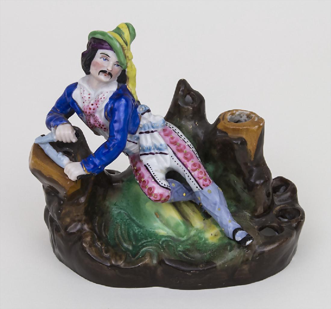 Figürlicher Pfeifenhalter / A figural pipe holder, wohl: Figürlicher Pfeifenhalter / A figural pipe holder, wohl Thüringen, Ende 19. Jh. Material: Porzellan, polychrom bemalt, Marke: ungemarkt, Dekor: über Natursockel Jäger im Rokoko-Gewand mit Messer u