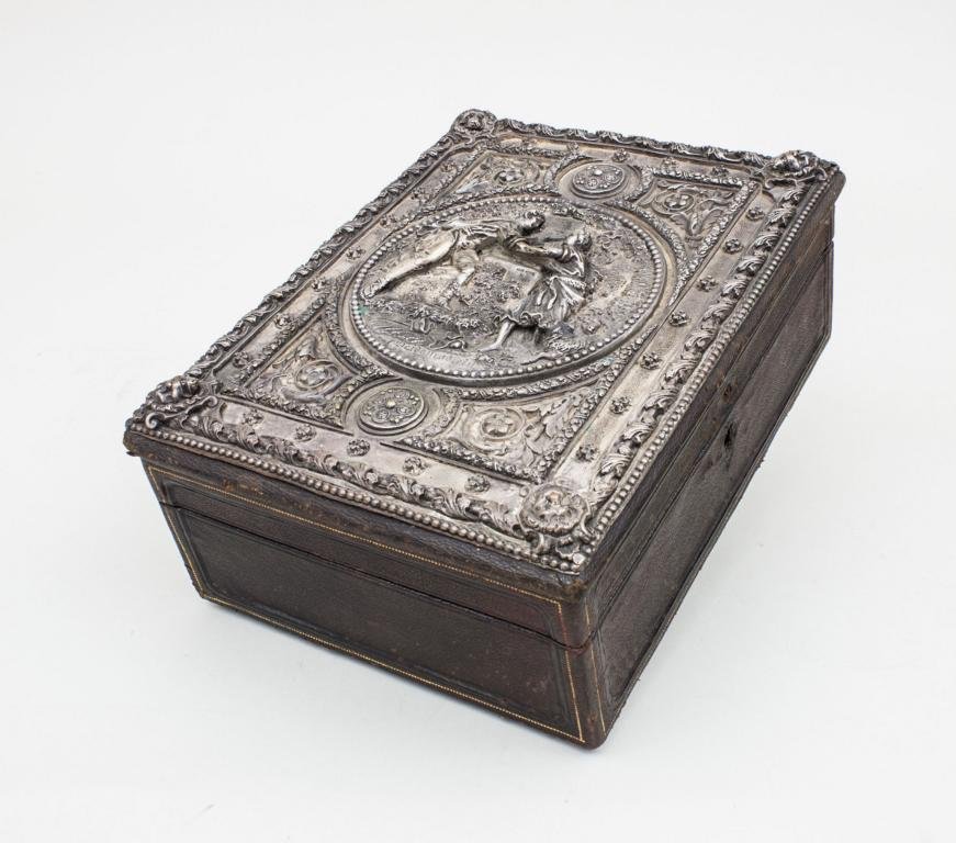 Buch-Schatulle/Book Case, sign. Gustav Grohe (1829-190): Buch-Schatulle/Book Case, sign. Gustav Grohe (1829-190) lederbezogene Holzschatulle in Buchform mit Scharnierdeckel und Schloss (Schlüssel fehlt). Auf Deckel Zinngussplatte mit halbplastischer, zentr