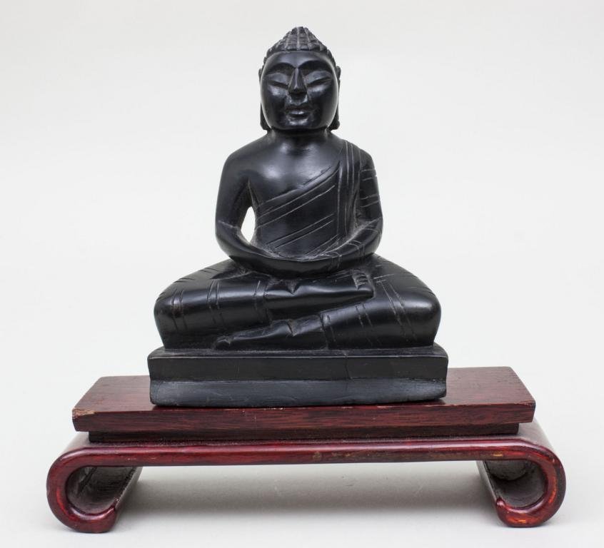 Buddha, 20. Jh. Material: Ebenholz, geschnitzt, auf: Buddha, 20. Jh. Material: Ebenholz, geschnitzt, auf Rosenholzsockel Mae: 13,5 cm (ohne Sockel) Zustand: Sockel mit Benutzungsspuren, 1 Eckbestoung [ak] Material: carved ebony, rosewood plinth Dimensio