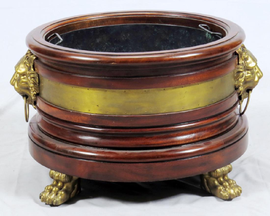 ENGLISH REGENCY MAHOGANY AND GILT BRASS PLANTER: ENGLISH REGENCY, MAHOGANY AND GILT BRASS PLANTER, C1830, H 17", DIA 24":Made of mahogany, with brass lions head masks with brass wire ring handles with a brass band around the periphery. Brass paw fee
