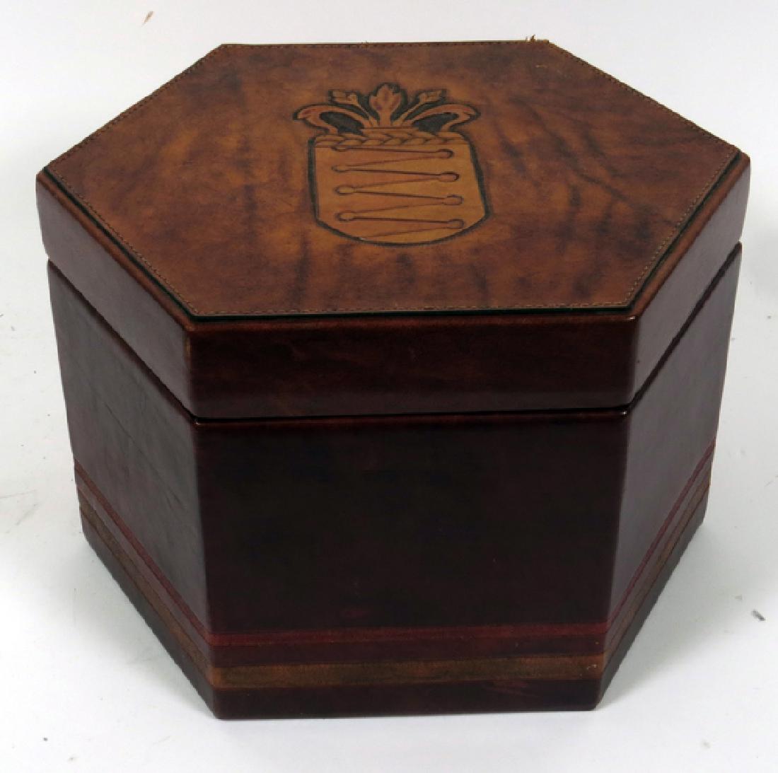 HEXAGONAL LEATHER CLAD HAT BOX C19TH C: HEXAGONAL, LEATHER CLAD, HAT BOX, C19TH C, H 8 1/2", DIA 12":A hexagonal leather clad hat box with a tooled coat of arms on the hinged lid. Opens to a black velvet lined interior.