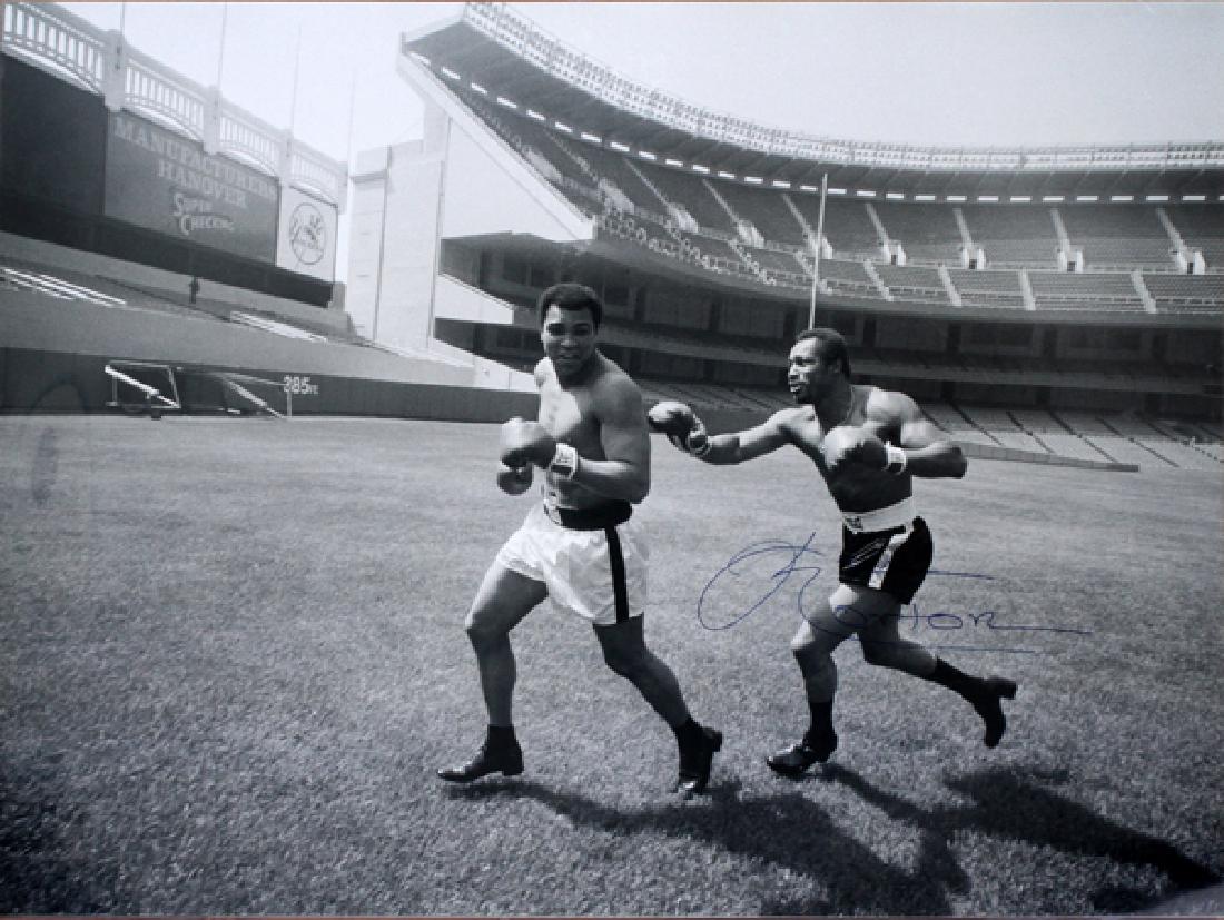 MUHAMMAD ALI & KEN NORTON PHOTO SIGNED BY NORTON: MUHAMMAD ALI AND KEN NORTON BLACK AND WHITE PUBLICITY PHOTO PRINT, SIGNED BY NORTON, 1976, H 30", W 40":Black and white photo print depicting Muhammad Ali being chased by Ken Norton attired in boxing 