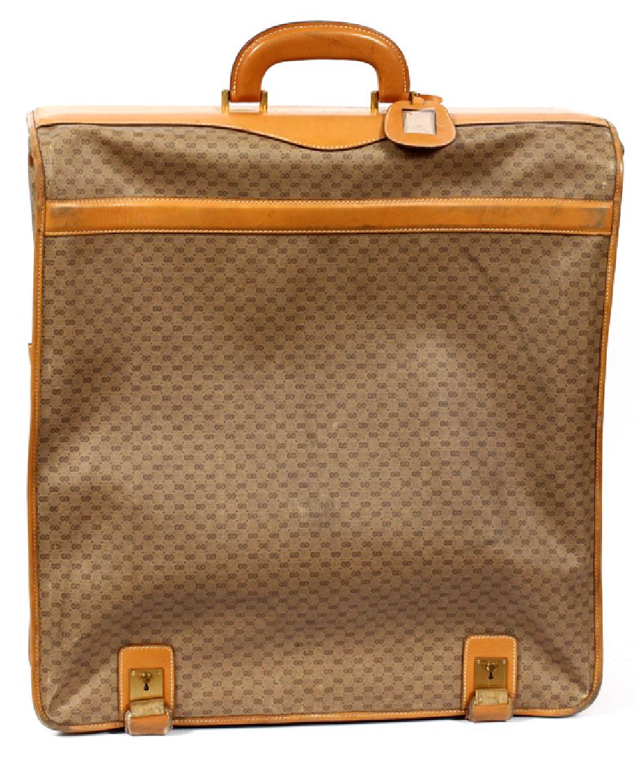 GUCCI BROWN MONOGRAM CANVAS GARMENT BAG: GUCCI BROWN MONOGRAM CANVAS HANGING GARMENT LUGGAGE BAG, H 23", W 20 1/2", L 5 3/4'':A vintage piece having brown leather handle and goldtone hardware. Main compartment has zipper opening with reinfor