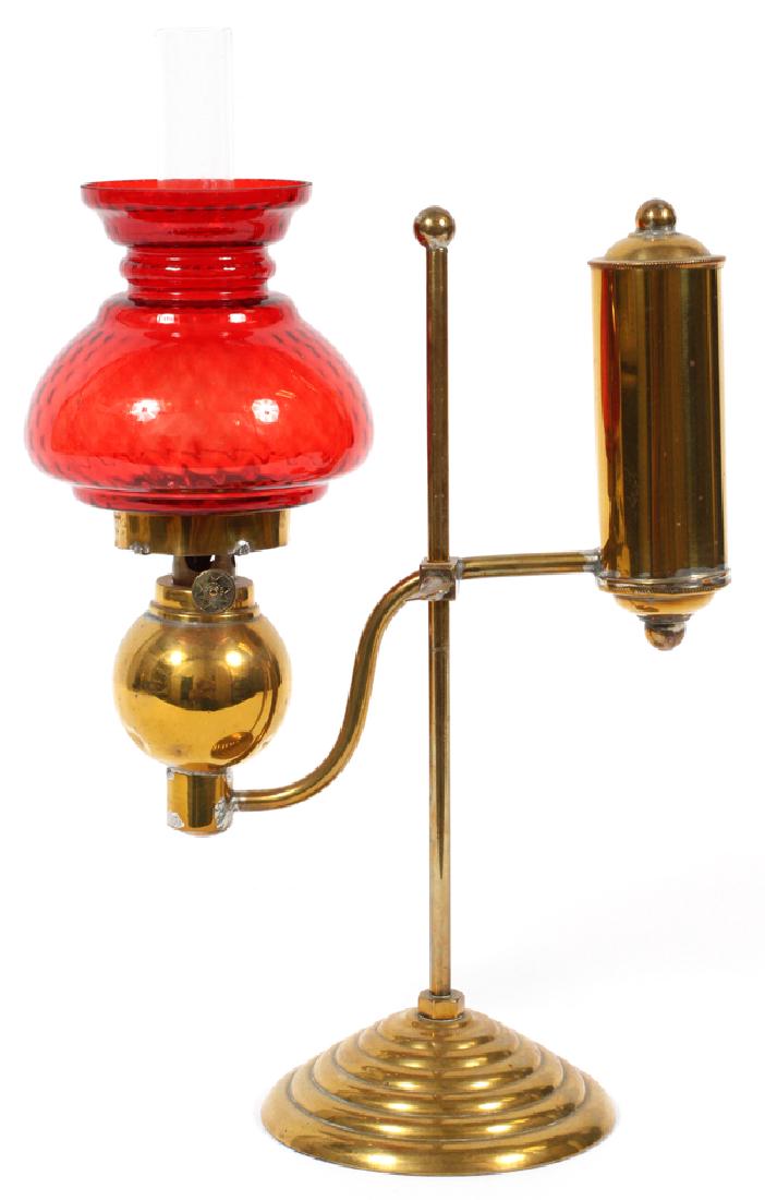 RED GLASS AND BRASS STUDENT LAMP: RED GLASS AND BRASS STUDENT LAMP, H 11", W 7 1/2":Red glass shade above a brass stand. Actual size: 11 1/2" H. x 7 1/2" W.