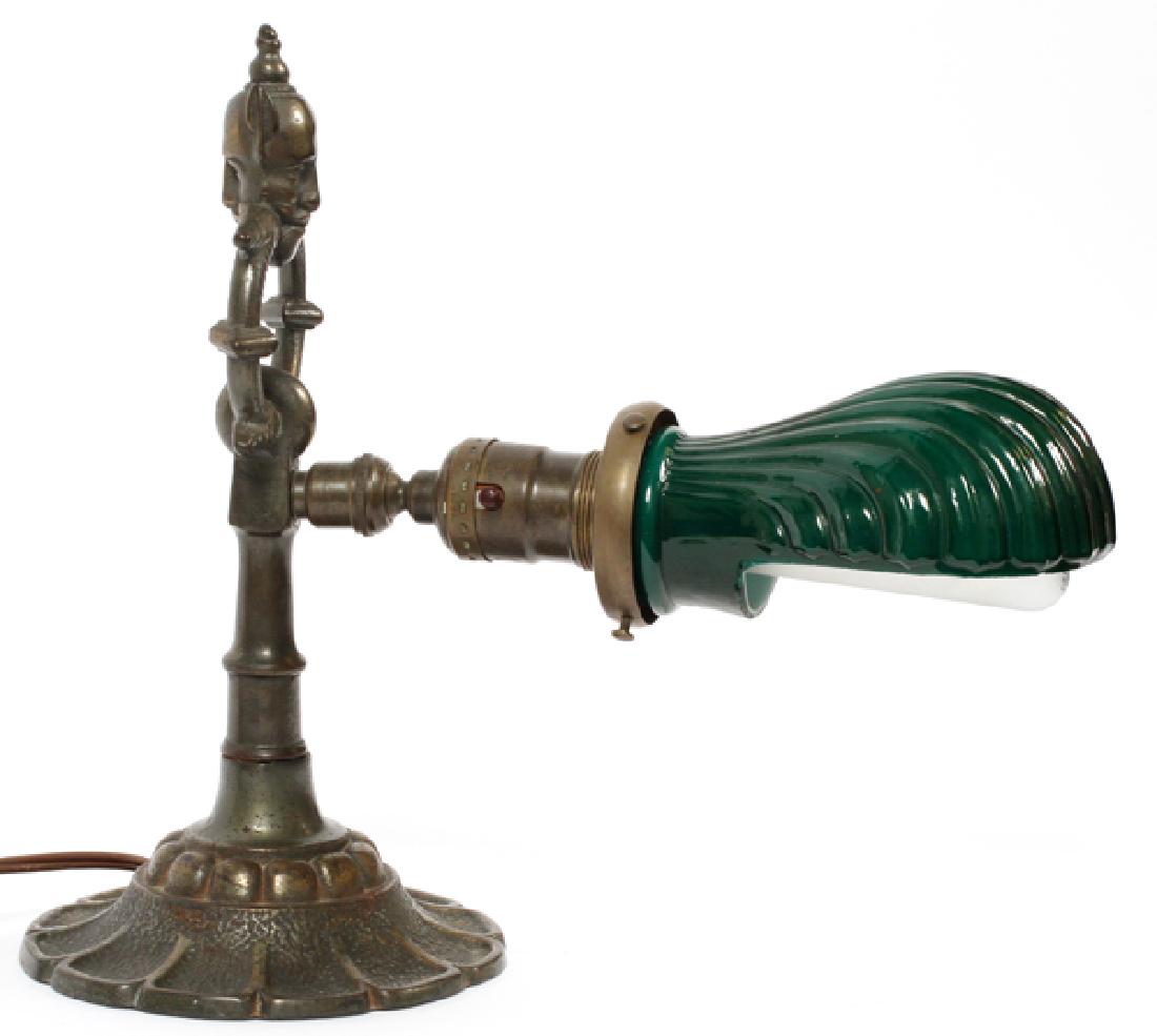 REMBRANDT GREEN GLASS AND WHITE METAL MASK LAMP: REMBRANDT GREEN GLASS AND WHITE METAL MASK LAMP, W 12":Marked to the base: Rembrandt #7159B. A mask finial above a ring and floral form flared base. Measures overall H.10 1/2" x 12". Electrified.