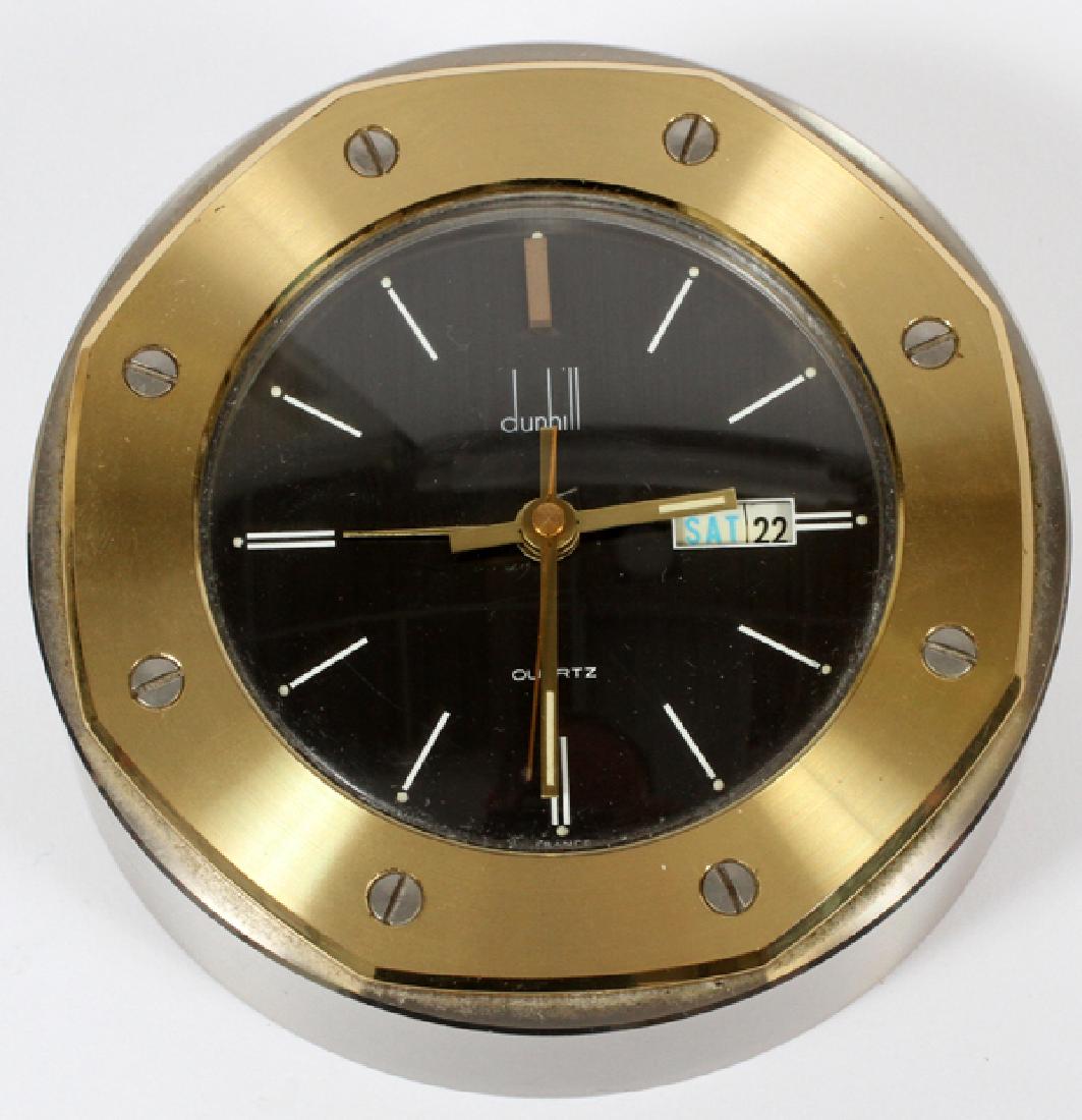 DUNHILL DESK CLOCK: DUNHILL DESK CLOCK, DIA 4":Having a gilt metal case with flat head stainless screws around bezel. Black face with day date at 3:00. Quartz movement. Marked "Dunhill" below 12:00.