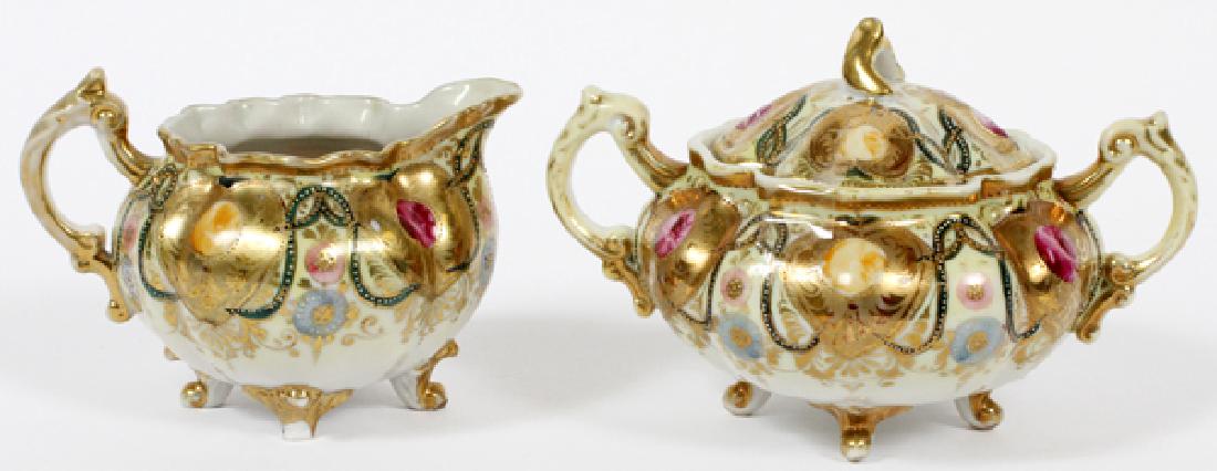 NORIMAKI HAND PAINTED PORCELAIN CREAMER AND SUGAR: NORIMAKI HAND PAINTED PORCELAIN CREAMER AND SUGAR H 5", W 7" & 8":having a ruffled rim, bulbous shape, footed with fired gold accents. 'Royal Nippon' marks on the undersides.