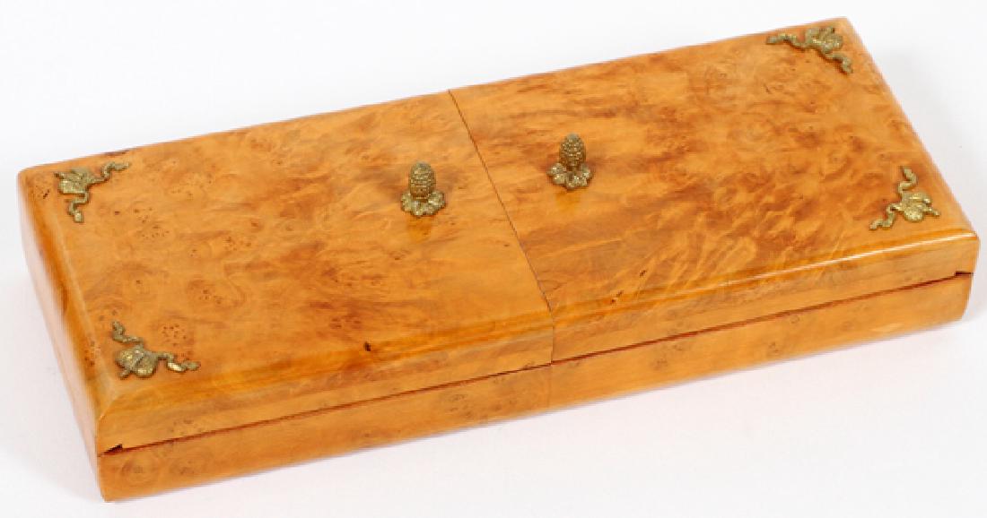 EDWARDIAN AMBOYNA LIDDED BOX: EDWARDIAN AMBOYNA LIDDED BOX, H 2", L 8 1/2", D 3 1/4":Having an ormolu mount in the shape of a crown with trailing ribbons to each corner, and having two pinecone finial handles to center of hinged d