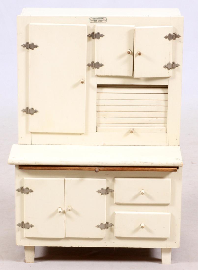 SCHOENHUT MINIATURE HOOSIER CABINET: SCHOENHUT MINIATURE HOOSIER CABINET, H 25", W 17":A painted white Hoosier style kitchen cabinet, with tin flour container at interior cupboard. Labeled to the front upper edge. 25" H. x 17 1/2" W.