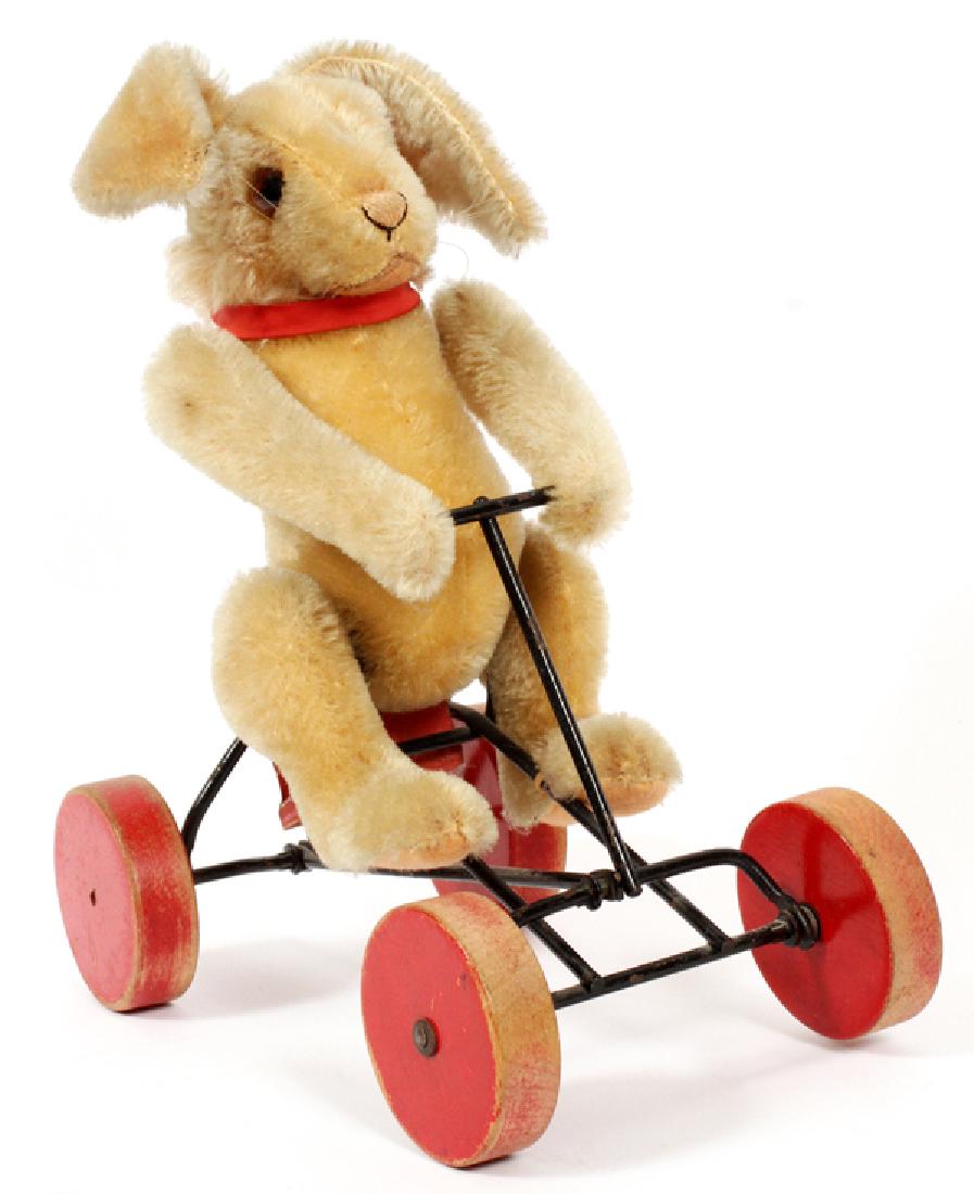 STEIFF MECHANICAL BUNNY TOY: STEIFF MECHANICAL BUNNY TOY, H 11", W 5", L 9":A MOHAIR UPRIGHT BUNNY RABBIT RIDING A MECHANICAL WHEELED TOY. MEASURES OVERALL H.11" X 9" X 5 1/4" APPROXIMATELY. WITH ORIGINAL TAG IN EAR.